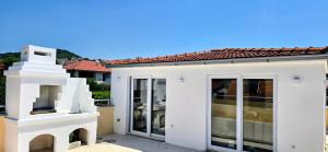 a white house with glass doors and a roof at Villa Imperial in Dobra Voda