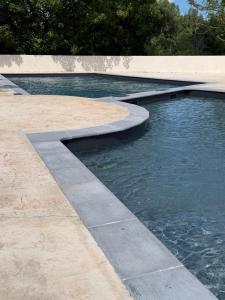 a pool of water in a park with a concrete curb at Chez Axel in Pradons