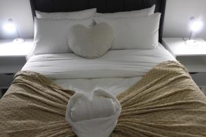 a bed with two heart shaped pillows on it at First Gen lagoon facing luxury apartment in Pretoria