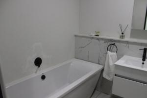a white bathroom with a tub and a sink at First Gen lagoon facing luxury apartment in Pretoria +9 photos