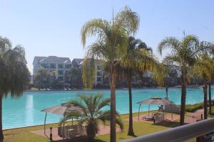 a view of a swimming pool with palm trees and umbrellas at First Gen lagoon facing luxury apartment in Pretoria