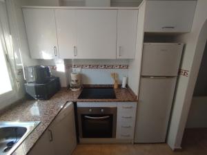 a kitchen with white cabinets and a sink and a refrigerator at Le paradis de Lynn in Formentera de Segura