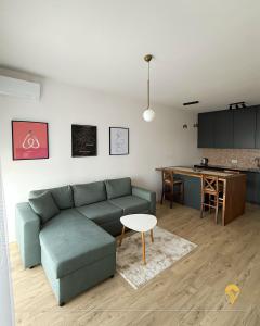 a living room with a green couch and a kitchen at Tian Vista Apartment in Prishtinë