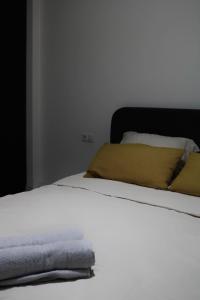a bed with white sheets and yellow pillows at Tian Vista Apartment in Prishtinë