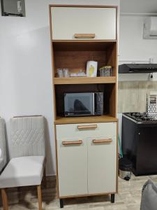 a cabinet with a microwave and a chair in a room at Apartamento no Centro de Macapá - Edifício Fernando Dias in Macapá
