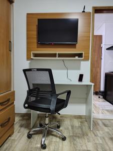 a black chair sitting in front of a desk with a tv at Apartamento no Centro de Macapá - Edifício Fernando Dias in Macapá