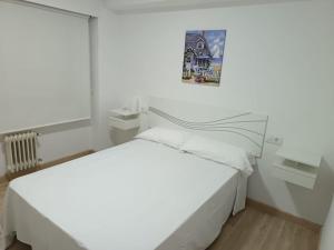 a white bedroom with a bed and a picture on the wall at Piso vacacional YaraMaya in Carballino