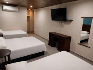 ein Hotelzimmer mit zwei Betten und einem Fernseher in der Unterkunft Hotel Tradicional Savaro SA de CV in Zihuatanejo