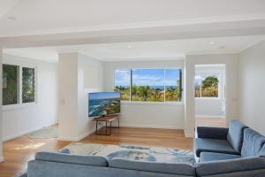 a living room with a blue couch and a large window at Wild Views in Tathra