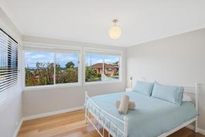 a white bedroom with a bed and two windows at Wild Views in Tathra