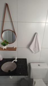 a bathroom with a sink and a mirror and a toilet at Quarto Recando do Sol in Aracaju