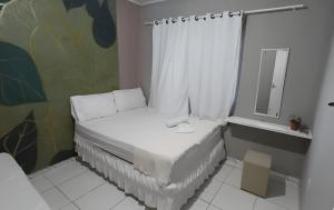a small white bed in a room with a mirror at Quarto Recando do Sol in Aracaju