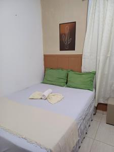 a bed with two green pillows and a phone on it at Quarto Recando do Sol in Aracaju