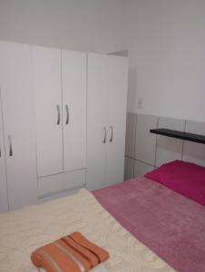 a bedroom with white cabinets and a pink bed at Casa no centro - perto de tudo in Itaguaí