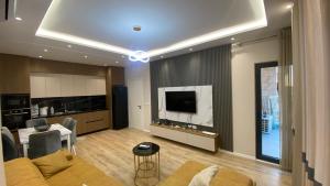 a living room with a couch and a tv and a kitchen at SL Apartment in Tirana