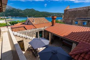 a patio with two umbrellas and a building with water at Apartments and rooms by the sea Slano, Dubrovnik - 2687 in Slano