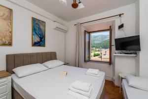 a white bedroom with a bed and a window at Apartments and rooms by the sea Slano, Dubrovnik - 2687 in Slano