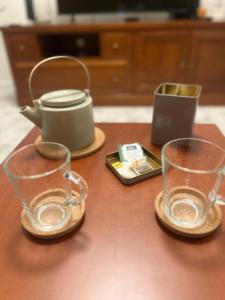 two glasses and a tea pot on a wooden table at On the Beach at Amorosa in Viana do Castelo