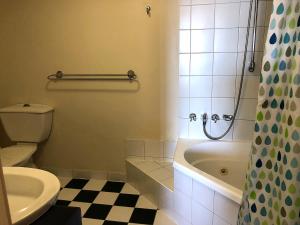a bathroom with a toilet and a tub and a sink at Sea Eagles Unit 4 in Caloundra