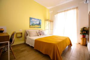 a yellow bedroom with a bed and a desk at Pole Pole - SOLE in Agropoli