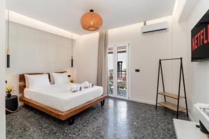 a bedroom with a large white bed and a tv at Maistrali city suites in Agios Nikolaos