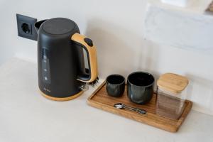 a tea kettle and two cups on a wooden tray at Maistrali city suites in Agios Nikolaos
