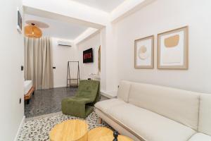 a living room with a white couch and a green chair at Maistrali city suites in Agios Nikolaos