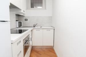 a white kitchen with white cabinets and a sink at Piazza Duomo Cathedral View in Brescia +7 photos