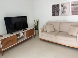 a living room with a couch and a flat screen tv at Apartamento no Centro in Muriaé