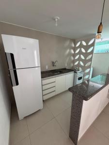 a kitchen with a white refrigerator and a sink at Apartamento no Centro in Muriaé