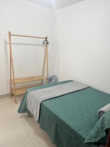 a bedroom with a bed with a green blanket at Apartamento no Centro in Muriaé +2 photos