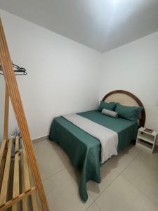 a bedroom with a bed with green sheets and a ladder at Apartamento no Centro in Muriaé