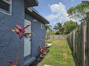 a blue house with a plant next to a fence at Hideaway Steps off Atlantic Ave - Private Studio in Delray Beach