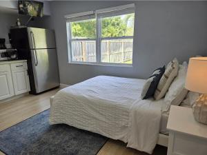 a bedroom with a white bed and a refrigerator at Hideaway Steps off Atlantic Ave - Private Studio in Delray Beach