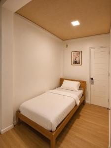 a bedroom with a bed with white sheets and a door at GASA Guesthouse in Compostela