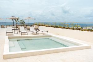 a swimming pool on top of a resort with the ocean at Hotel Indigo Playa del Carmen by IHG in Playa del Carmen