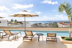 a patio with chairs and an umbrella and a pool at Hotel Indigo Playa del Carmen by IHG in Playa del Carmen +89 photos