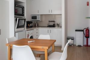 a kitchen with a wooden table and white chairs at Casa da Quinta da Azeitona 2 - Piscina privada e BBQ na Serra da Gardunha in Fundão