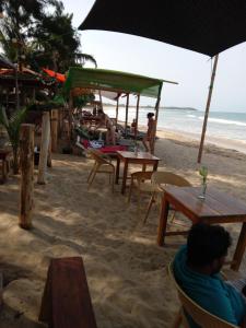 a group of people sitting at tables on the beach at Beach Cab Resort in Arugam Bay