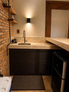 a kitchen with a sink and a brick wall at Casa Naru in Atins