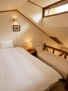 a bedroom with two beds and a window at Country Inn Milky House in Niseko