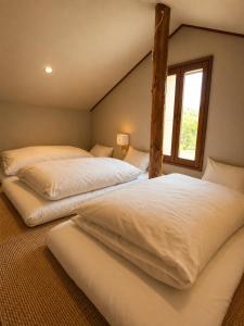 two beds in a room with a window at Country Inn Milky House in Niseko +177 photos