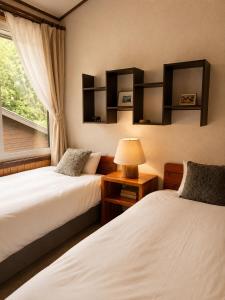 two beds in a room with a window and a lamp at Country Inn Milky House in Niseko