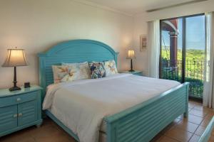 a bedroom with a blue bed and a balcony at Spacious 4BR Condo with Partial Ocean View - Bougainvillea - Reserva Conchal in Playa Conchal