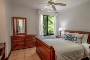 a bedroom with a bed and a mirror and a window at Spacious 4BR Condo with Partial Ocean View - Bougainvillea - Reserva Conchal in Playa Conchal