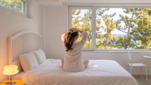 a woman sitting on a bed looking out the window at Samcheok Migaloo Pool Villa Pension in Samcheok