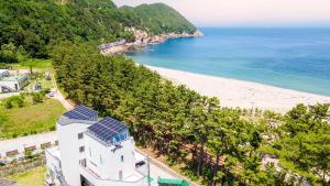 a white house with solar panels on the beach at Samcheok Migaloo Pool Villa Pension in Samcheok