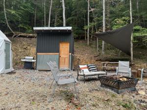 a small shed with chairs and a fire pit at The Perch Glamping by Rafting in Cosby
