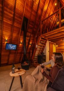 two people sitting in a living room with a fireplace at Cabana com banheira in Gramado