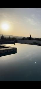 a pool of water with the sun setting in the background at Hammamet villa Bleu in Hammamet